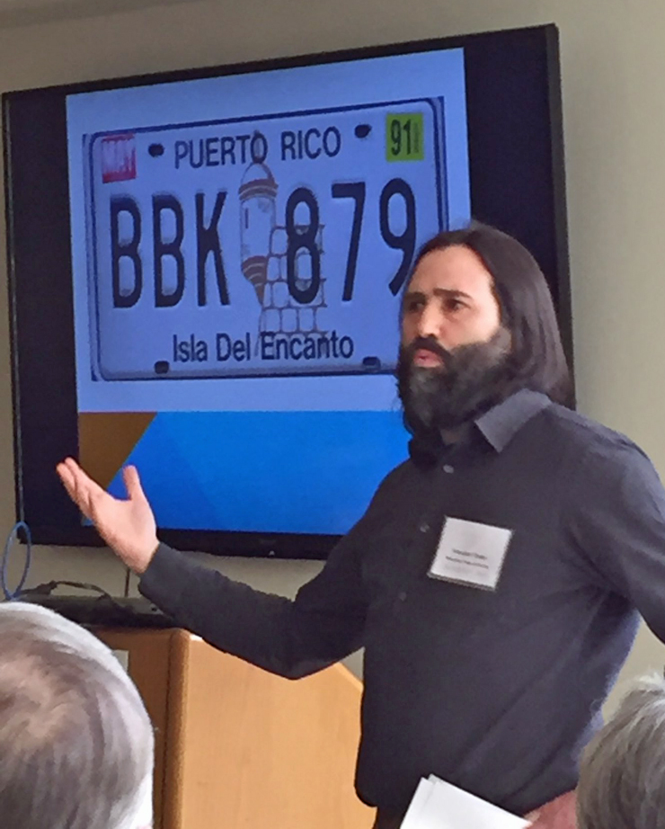 A man speaking in front of a screen with an image of a Puerto Rican car license plate